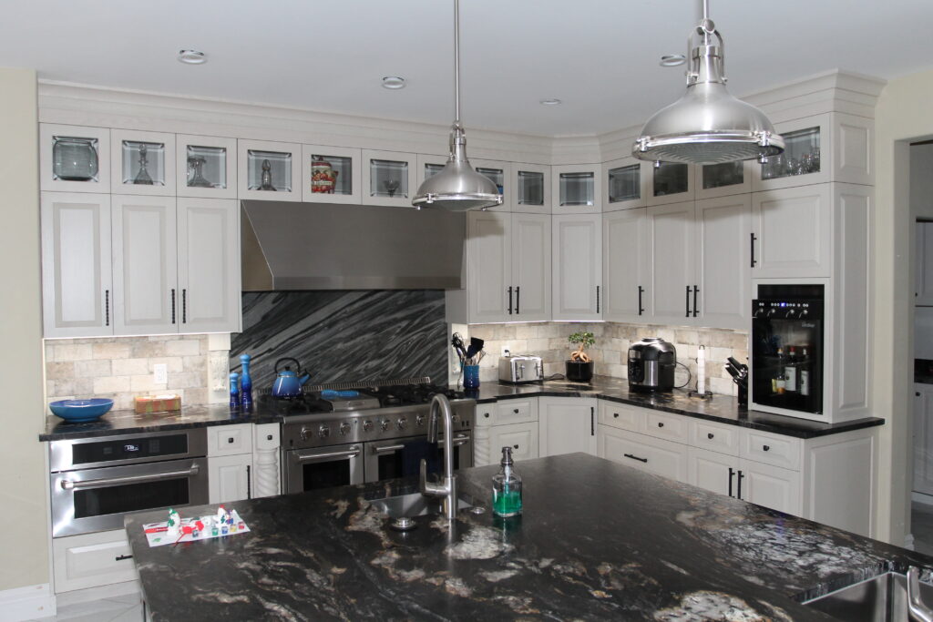 Renovated Calgary kitchen with white shaker cabinets, dark granite island and stainless pendant lights