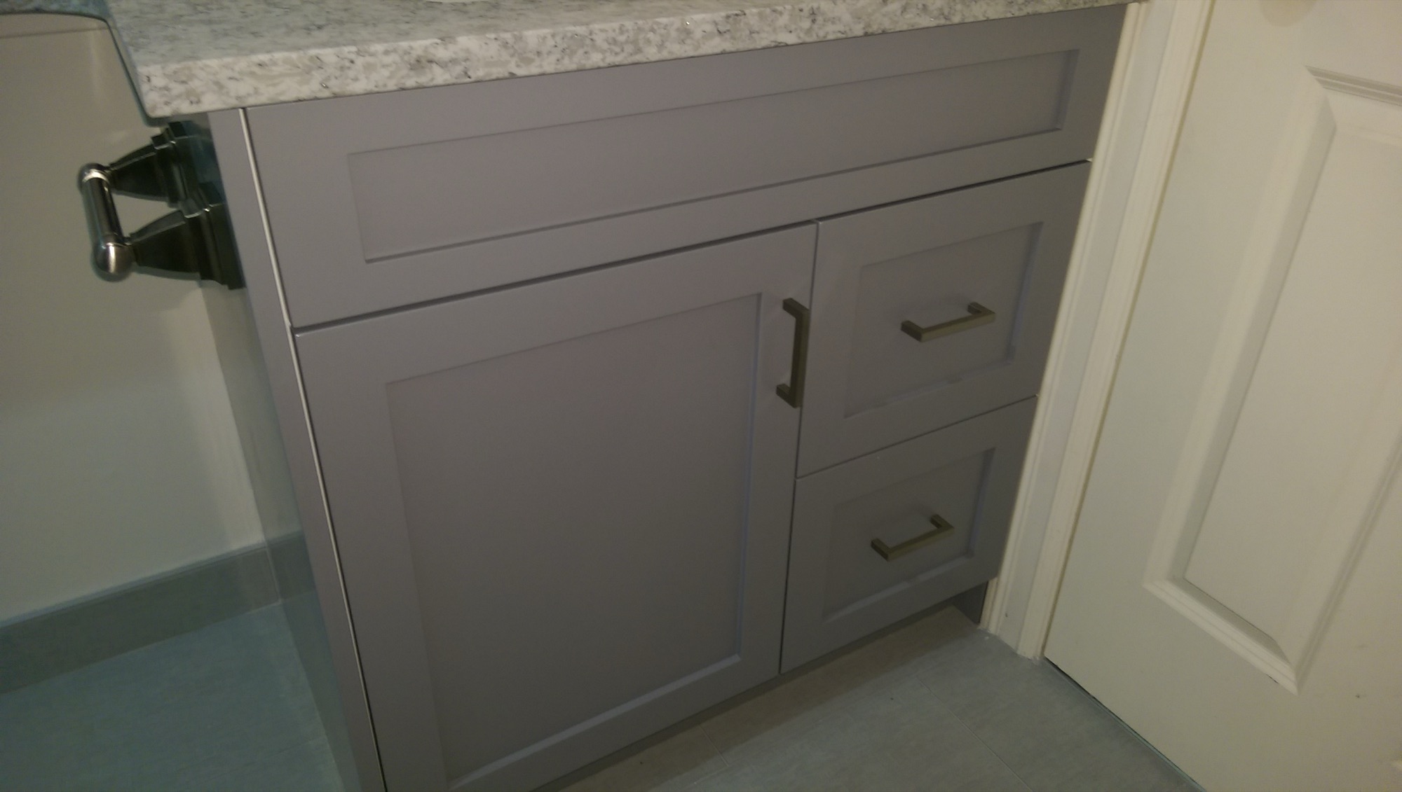 Grey shaker bathroom vanity with granite top and dark bronze pulls