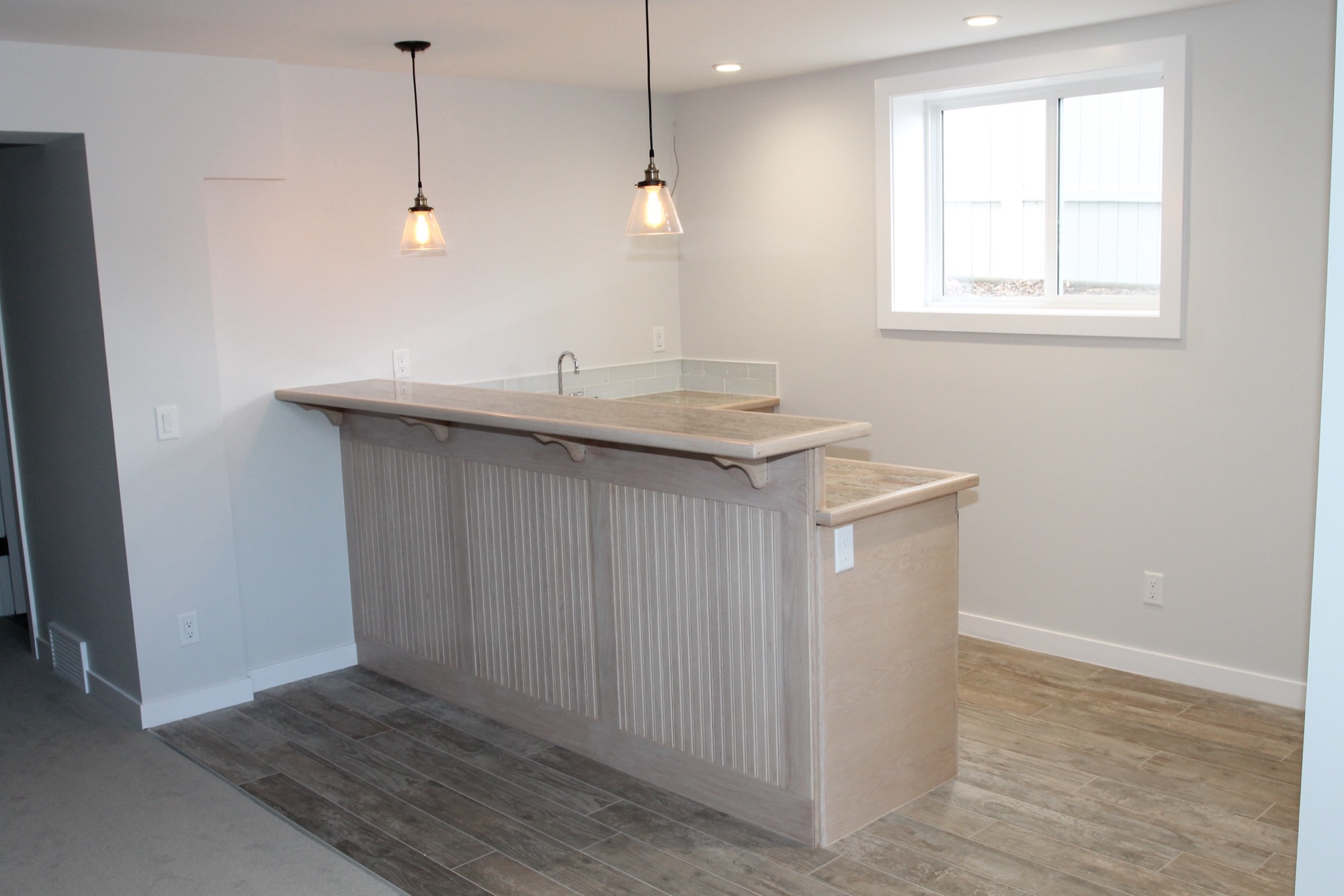 Basement wet bar with granite counter and pendant lighting