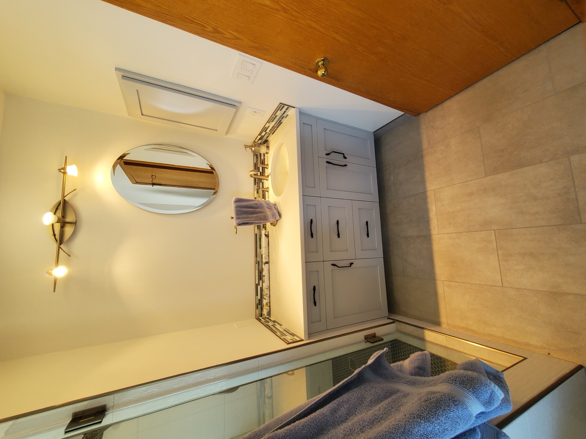 Bathroom vanity with brass fixtures and round mirror
